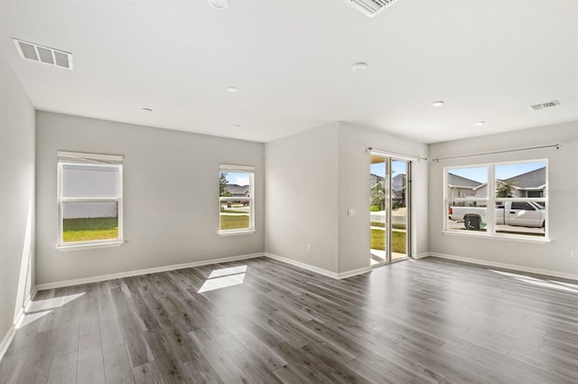 spare room featuring plenty of natural light, visible vents, and dark wood-style flooring