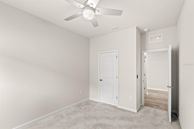 unfurnished bedroom with light carpet, a ceiling fan, visible vents, and baseboards