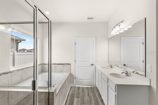 full bath with a garden tub, wood finished floors, a sink, and visible vents