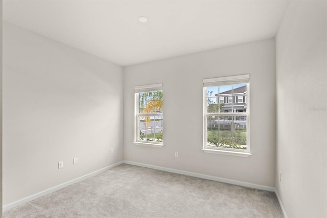 spare room featuring baseboards and light colored carpet