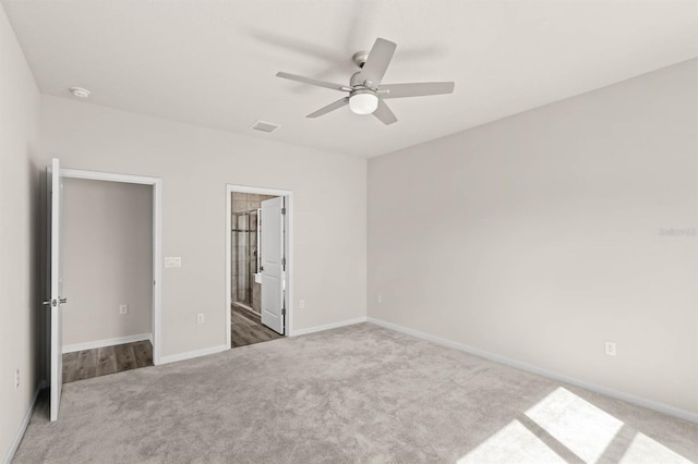 unfurnished bedroom with visible vents, dark carpet, baseboards, and ensuite bathroom