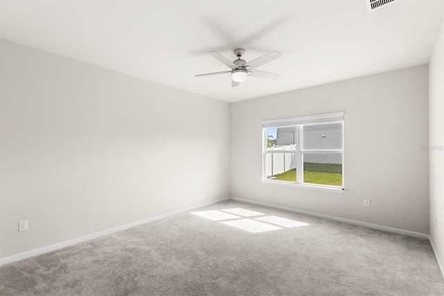 carpeted spare room with ceiling fan and baseboards