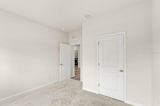 unfurnished bedroom featuring light carpet, baseboards, and visible vents