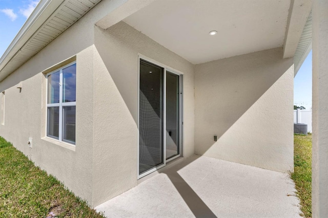 entrance to property with a patio, fence, and stucco siding