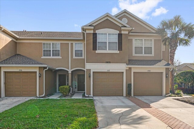 2851 Polvadero Ln Unit 107, Orlando, FL 32835 - townhome / multi-family property featuring stucco siding, concrete driveway, a front lawn, and an attached garage