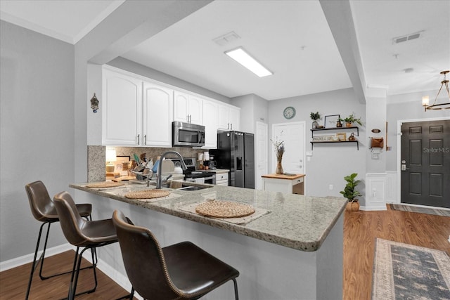 kitchen featuring stainless steel appliances, white cabinets, visible vents, and a peninsula