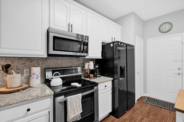 kitchen featuring white cabinets, appliances with stainless steel finishes, backsplash, light stone countertops, and light wood finished floors