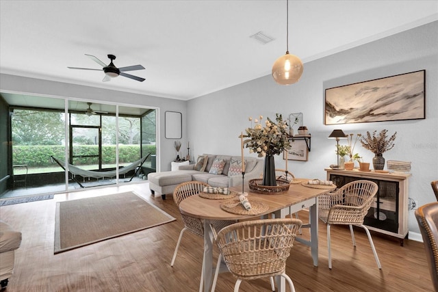 living room featuring ornamental molding, visible vents, ceiling fan, and wood finished floors