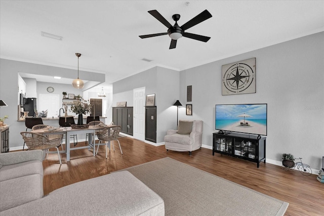 living room with visible vents, wood finished floors, a ceiling fan, and baseboards