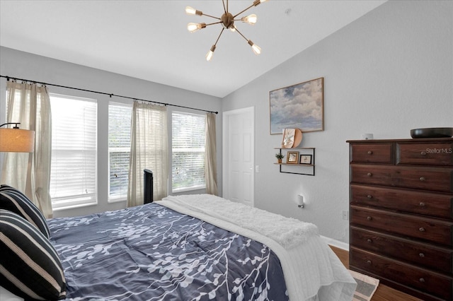 bedroom with a chandelier, wood finished floors, and lofted ceiling