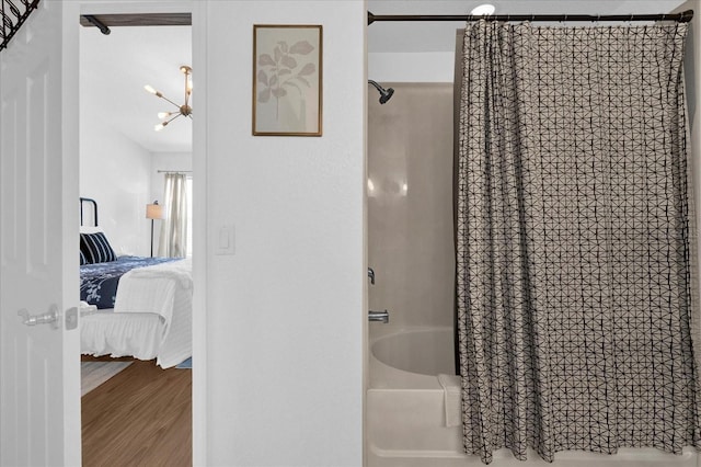 full bath featuring ensuite bathroom, an inviting chandelier, wood finished floors, and shower / tub combo with curtain