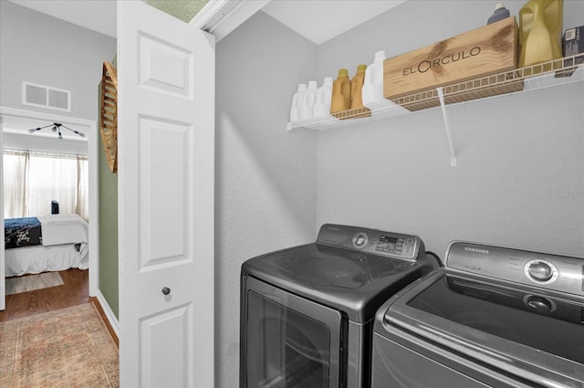 laundry room with visible vents, wood finished floors, washer and dryer, laundry area, and baseboards