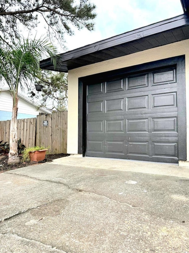 garage featuring driveway and fence