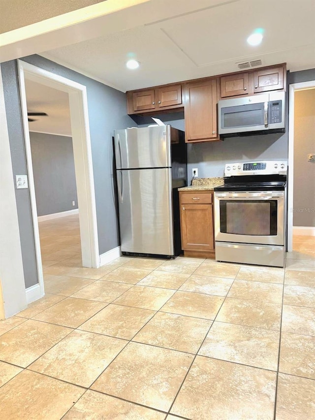 kitchen with light tile patterned floors, visible vents, brown cabinetry, appliances with stainless steel finishes, and light countertops