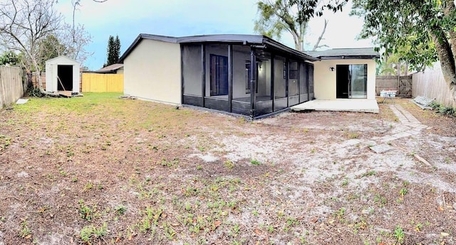 rear view of house featuring a storage unit, an outdoor structure, a fenced backyard, and a sunroom