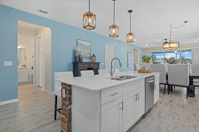 kitchen with light countertops, white cabinets, visible vents, and a center island with sink