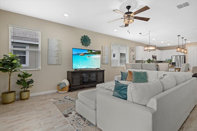 living area with ceiling fan, recessed lighting, visible vents, baseboards, and light wood-type flooring