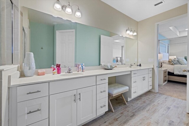 ensuite bathroom featuring visible vents, vanity, ensuite bath, and wood finished floors