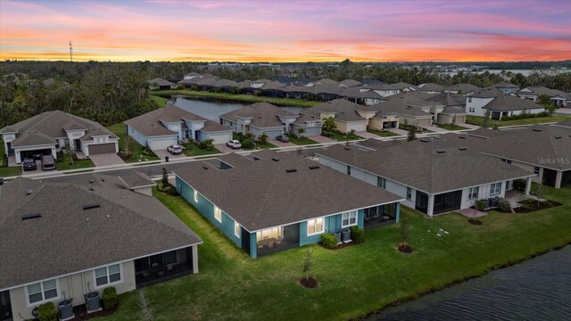 aerial view at dusk with a residential view and a water view