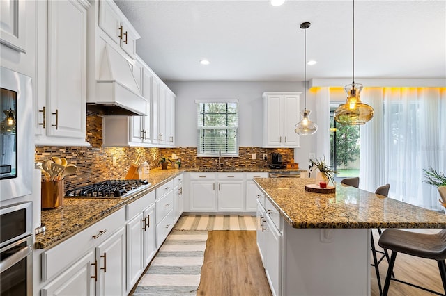 14664 Spotted Sandpiper Blvd, Winter Garden, FL 34787 - kitchen with a kitchen breakfast bar, white cabinetry, a center island, light wood-style flooring, and appliances with stainless steel finishes