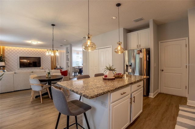 14664 Spotted Sandpiper Blvd, Winter Garden, FL 34787 - kitchen featuring stainless steel fridge with ice dispenser, light wood-style floors, white cabinetry, a kitchen island, and a breakfast bar area