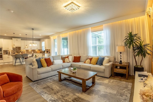 14664 Spotted Sandpiper Blvd, Winter Garden, FL 34787 - living area with light wood-style flooring, a textured ceiling, and a chandelier