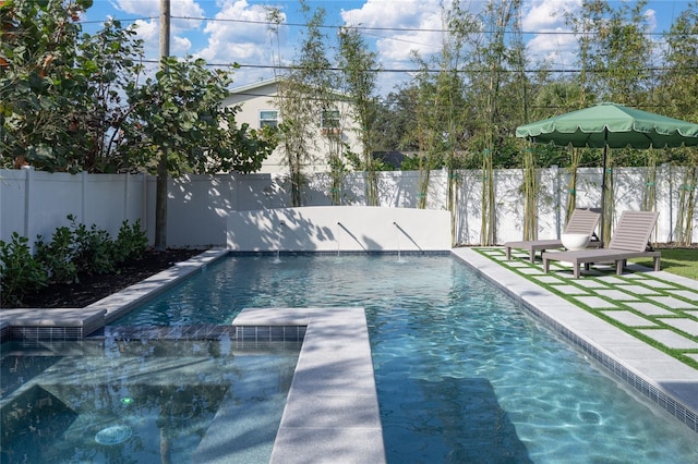 view of pool with a fenced backyard, a pool with connected hot tub, a diving board, and a patio