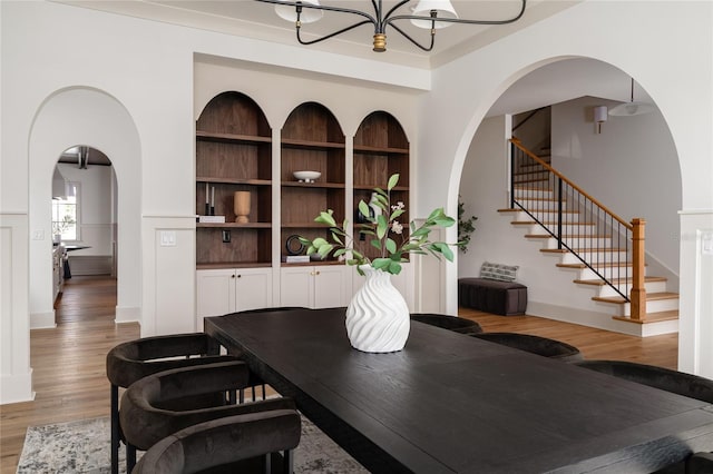 interior space with a notable chandelier, arched walkways, and wood finished floors