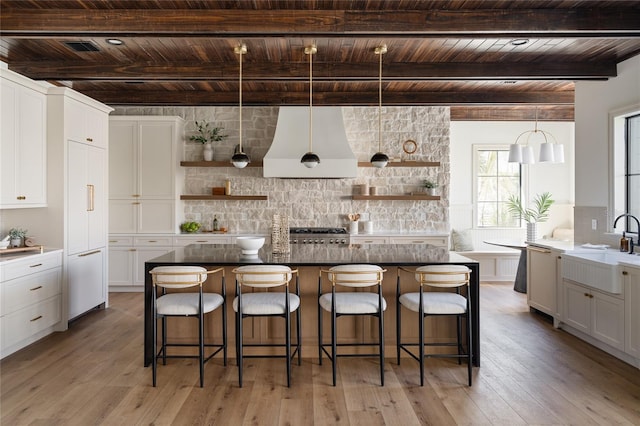 kitchen featuring a center island, wall chimney range hood, and open shelves