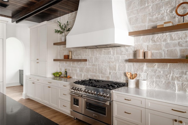 kitchen featuring range with two ovens, premium range hood, white cabinetry, light wood-type flooring, and open shelves