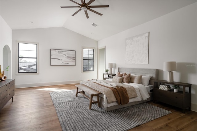 bedroom featuring baseboards, visible vents, a ceiling fan, lofted ceiling, and wood finished floors