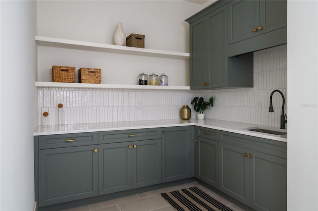 kitchen with open shelves, tasteful backsplash, light countertops, light tile patterned flooring, and a sink