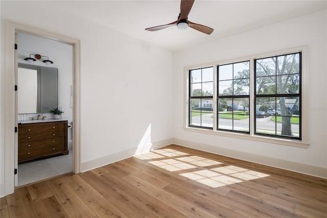 bedroom with multiple windows, a sink, light wood-style flooring, and baseboards