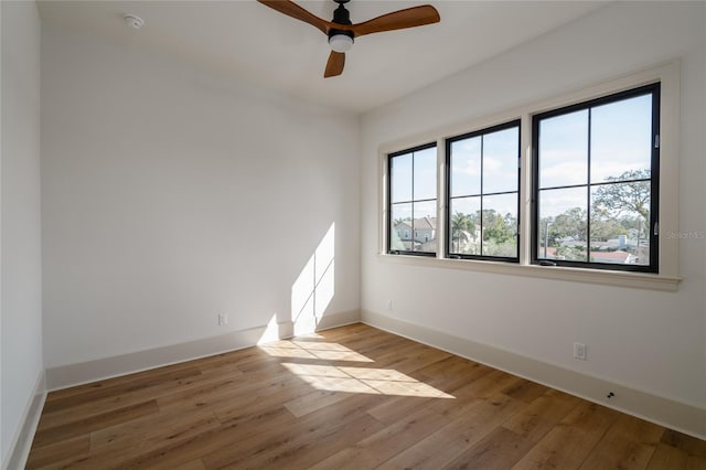 spare room featuring ceiling fan, light wood-style flooring, and baseboards