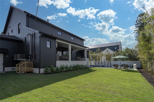 rear view of house featuring a ceiling fan, fence, a lawn, and a patio