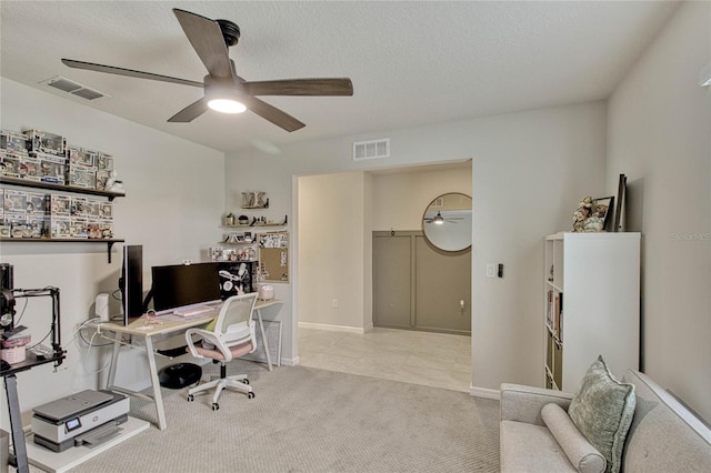 office featuring carpet floors, a ceiling fan, visible vents, and a textured ceiling