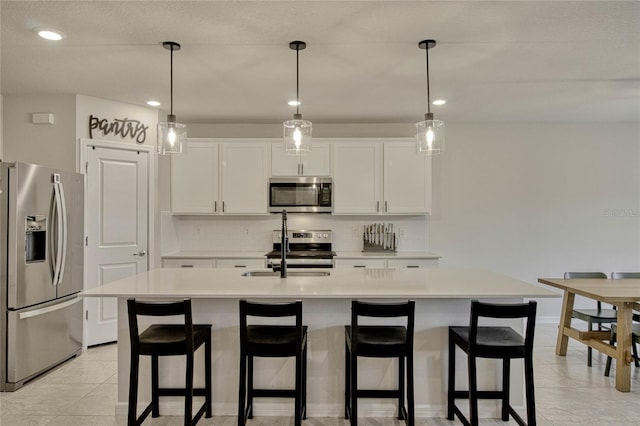 kitchen with light countertops, backsplash, appliances with stainless steel finishes, white cabinetry, and a sink