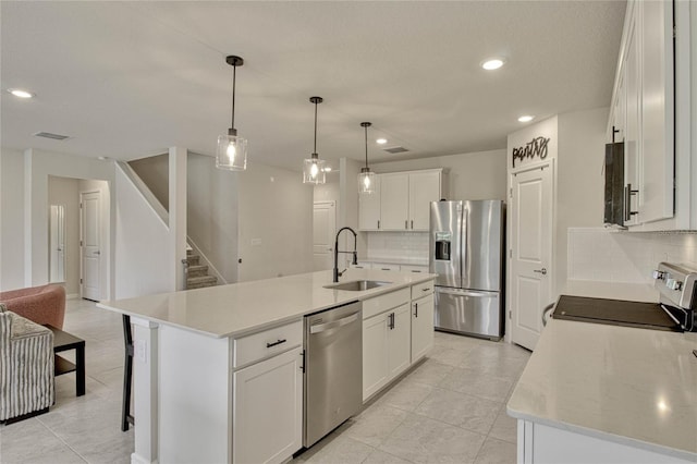 kitchen with an island with sink, stainless steel appliances, white cabinetry, a sink, and recessed lighting