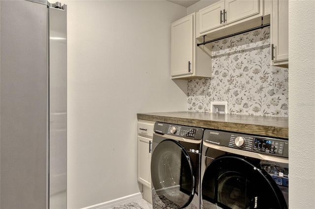 clothes washing area with baseboards, cabinet space, and washing machine and clothes dryer