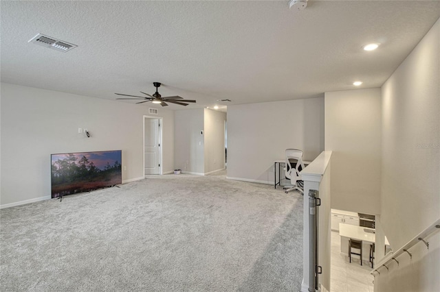 interior space featuring a textured ceiling, ceiling fan, light colored carpet, visible vents, and baseboards