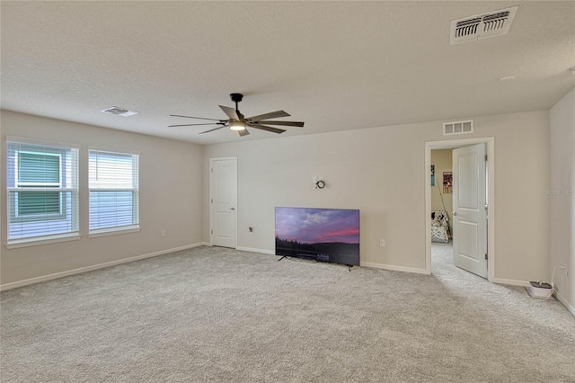 unfurnished living room with a textured ceiling, carpet, visible vents, and baseboards