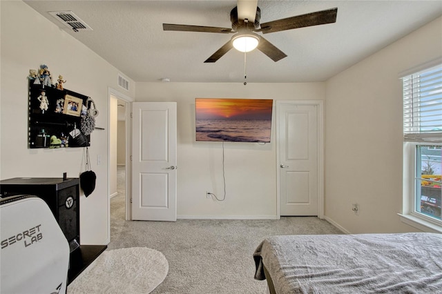 carpeted bedroom featuring a ceiling fan, visible vents, a textured ceiling, and baseboards