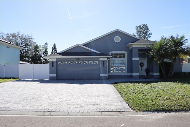 ranch-style house with a garage, a gate, decorative driveway, and stucco siding