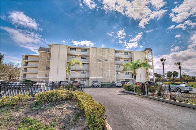 view of property with uncovered parking and fence