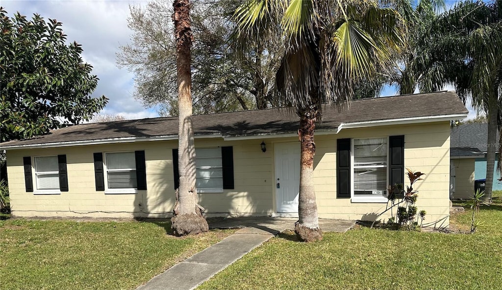 single story home featuring concrete block siding and a front yard