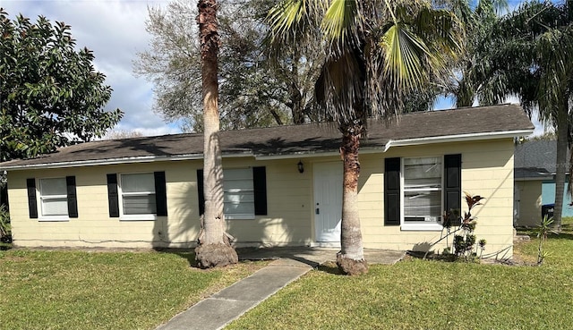 single story home featuring concrete block siding and a front yard