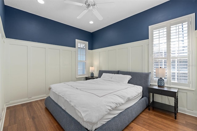 bedroom featuring multiple windows, wood finished floors, and wainscoting