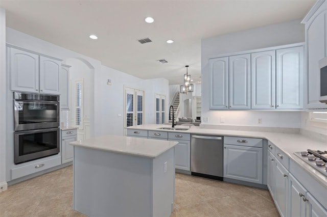 kitchen featuring light tile patterned floors, visible vents, appliances with stainless steel finishes, a center island, and a sink