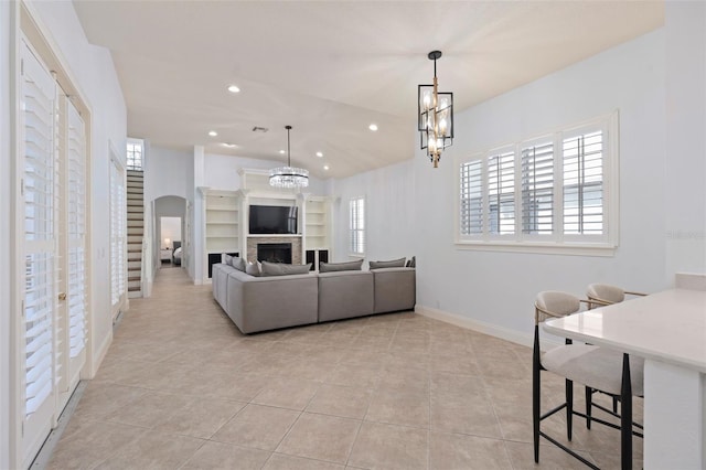 living room with arched walkways, a fireplace, light tile patterned floors, recessed lighting, and a chandelier