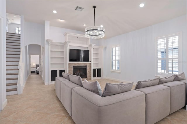 living room with light tile patterned floors, visible vents, arched walkways, a stone fireplace, and recessed lighting